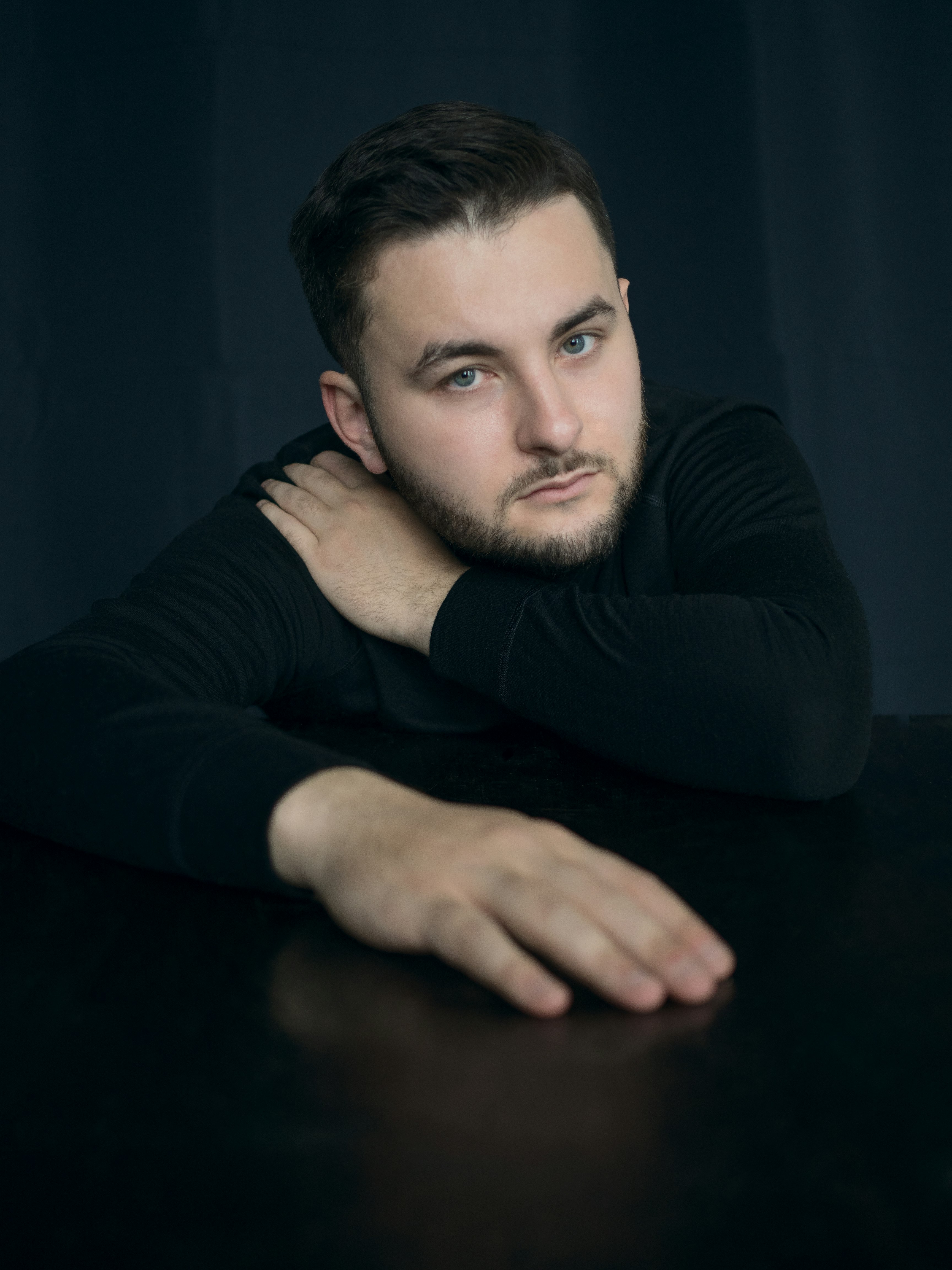 man in black long sleeve shirt leaning on brown wooden table